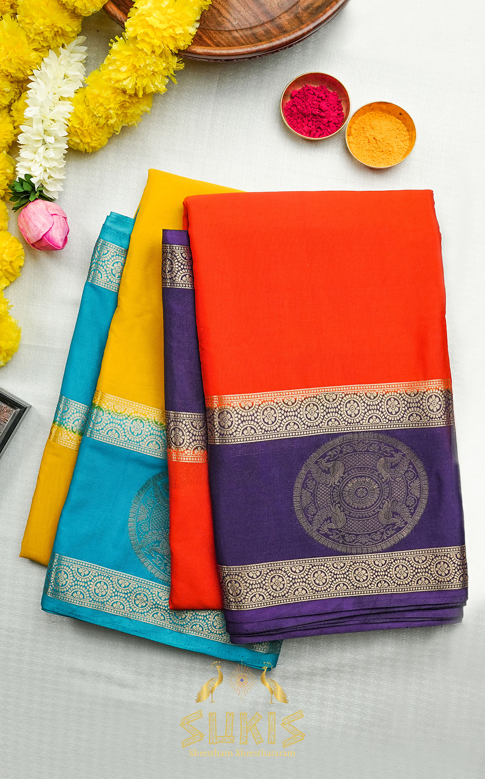 Colorful sarees with decorative patterns on a light gray background